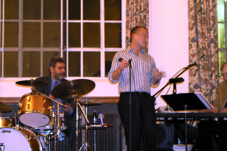 a man standing up on stage with microphone and music instruments