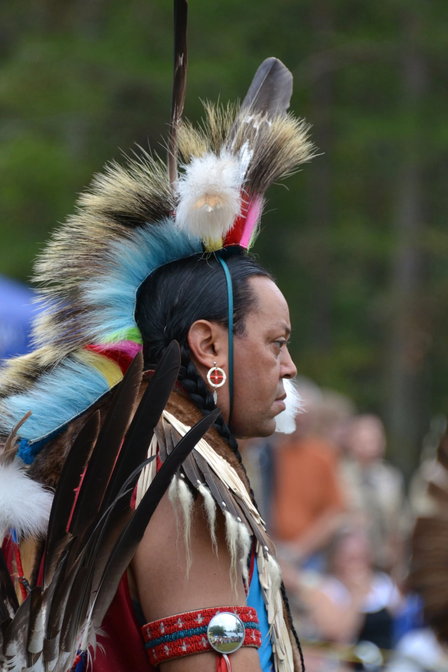 a native american man wearing feathers and looking away