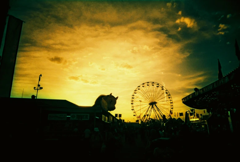 a ferris wheel is lit up in front of a sunset