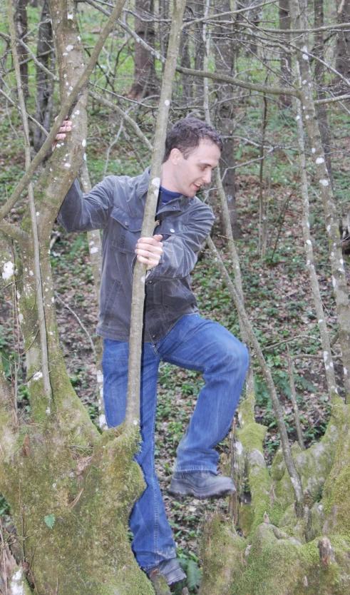 a man walking in the woods holding a stick