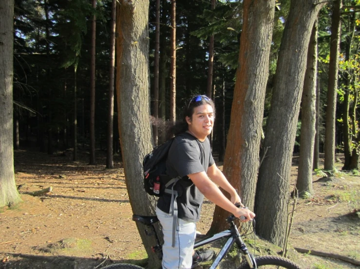 a man is standing by some trees while holding his bike