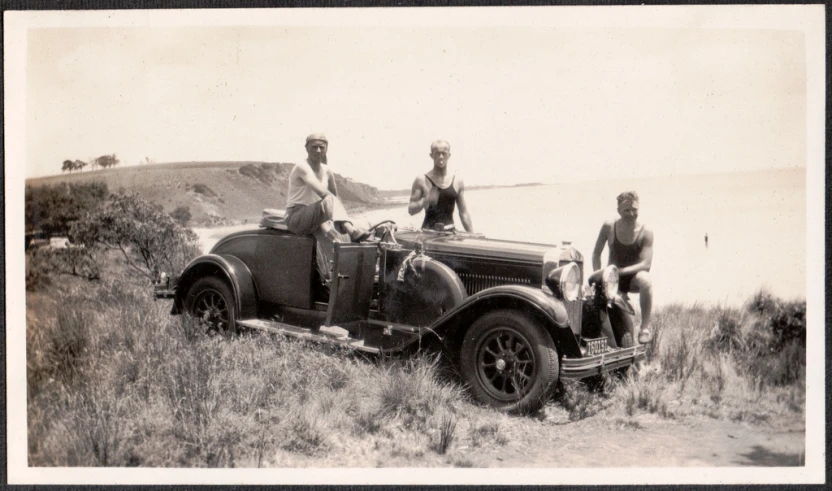 an old po with three people sitting in a old car on the road