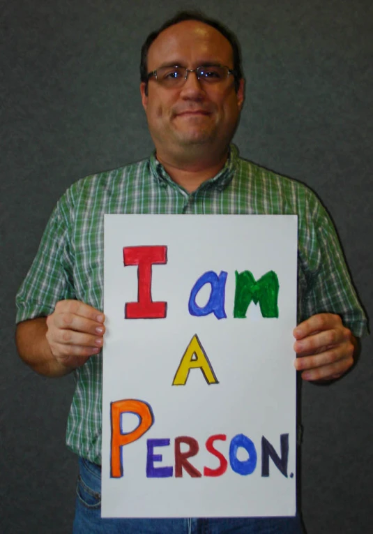 a man holding up a paper that says i am a person