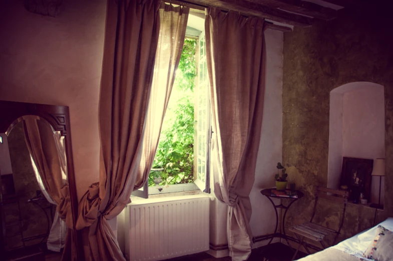 a bedroom is pictured with a window, mirror and radiator