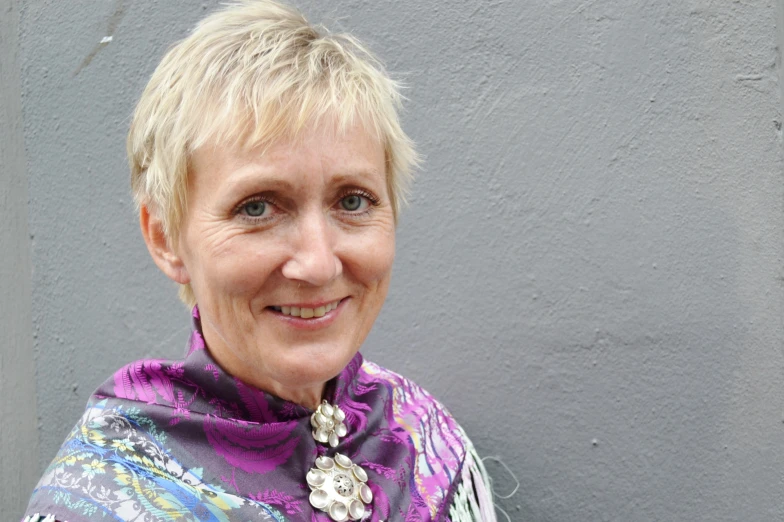 an older blonde haired lady wearing a colorful scarf and smiling