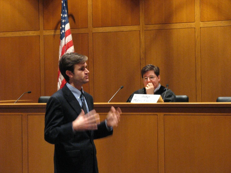 a woman in a black suit sitting at a table next to another man