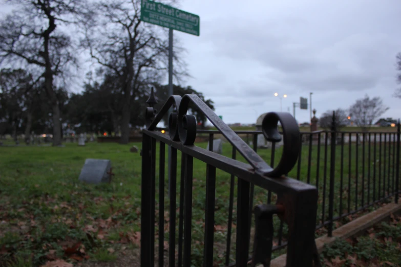 a gated grass yard that has a street sign and a grassy area behind it