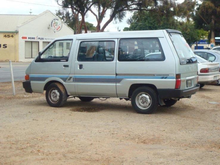 a small silver van parked in the middle of a parking lot