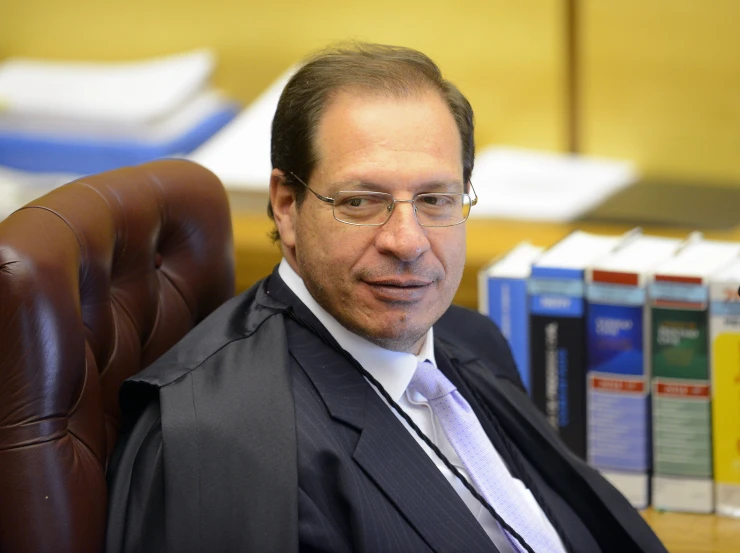 a man with glasses and suit coat sitting in chair