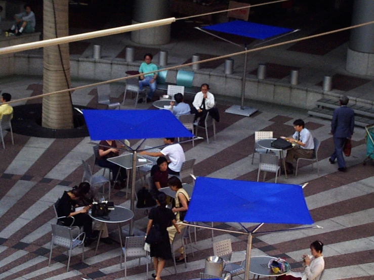 people are gathered together around small tables and chairs