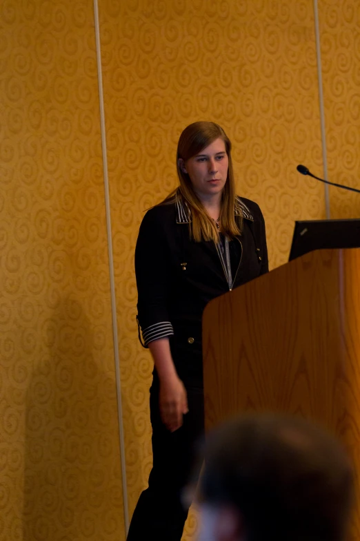 a girl stands at a podium talking to an audience