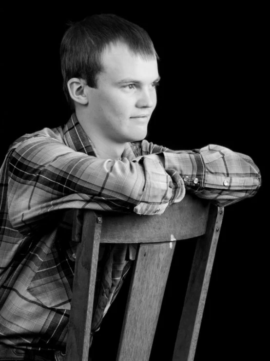 a man in a checkered shirt sitting on a chair