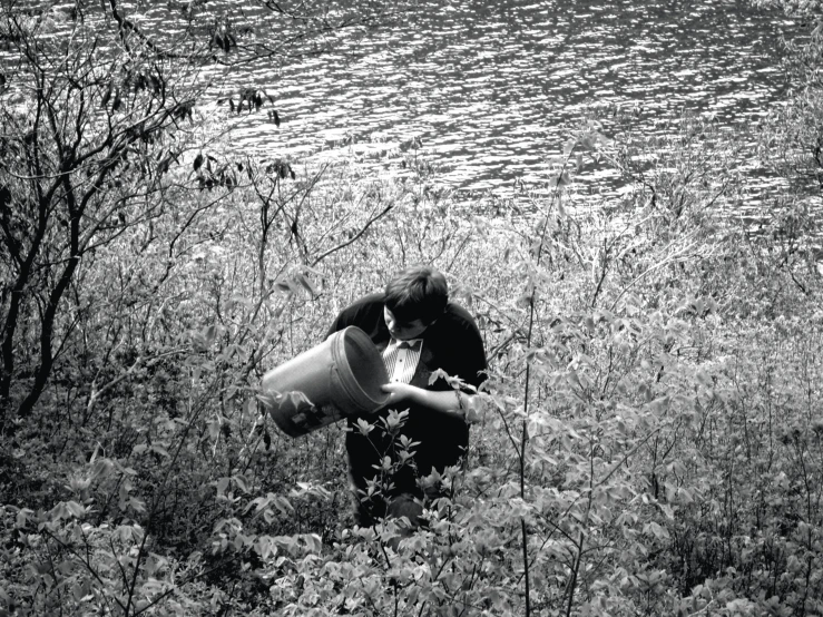 two people standing in a grass area next to some water