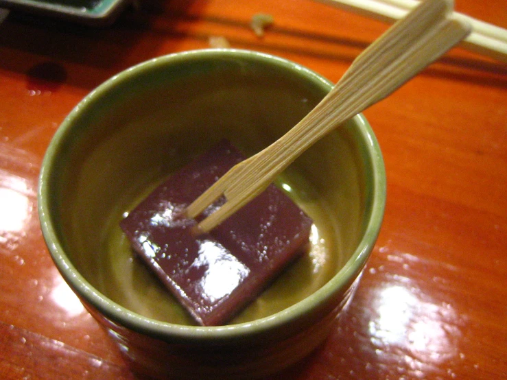 a bowl holding a bar of chocolate with chopsticks sticking out of it