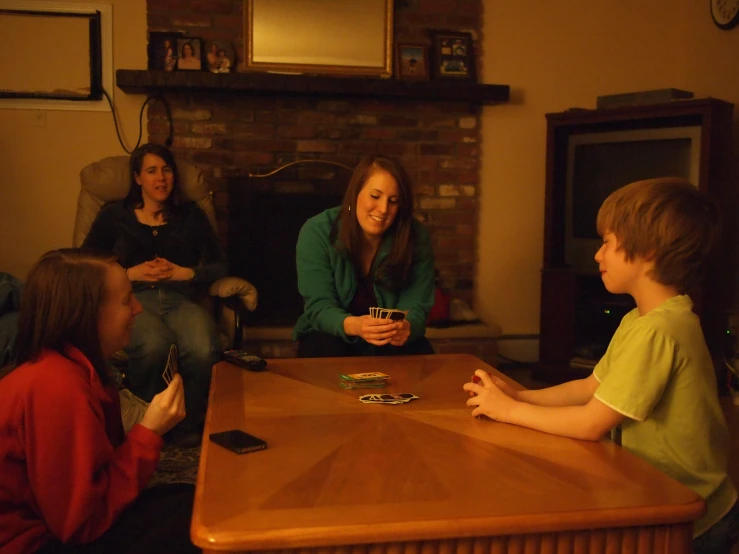 children are sitting around a wooden table playing cards