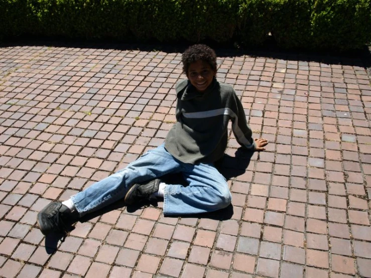 a  smiling while sitting on a brick walkway