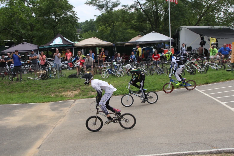 several people ride bicycles in front of a tent