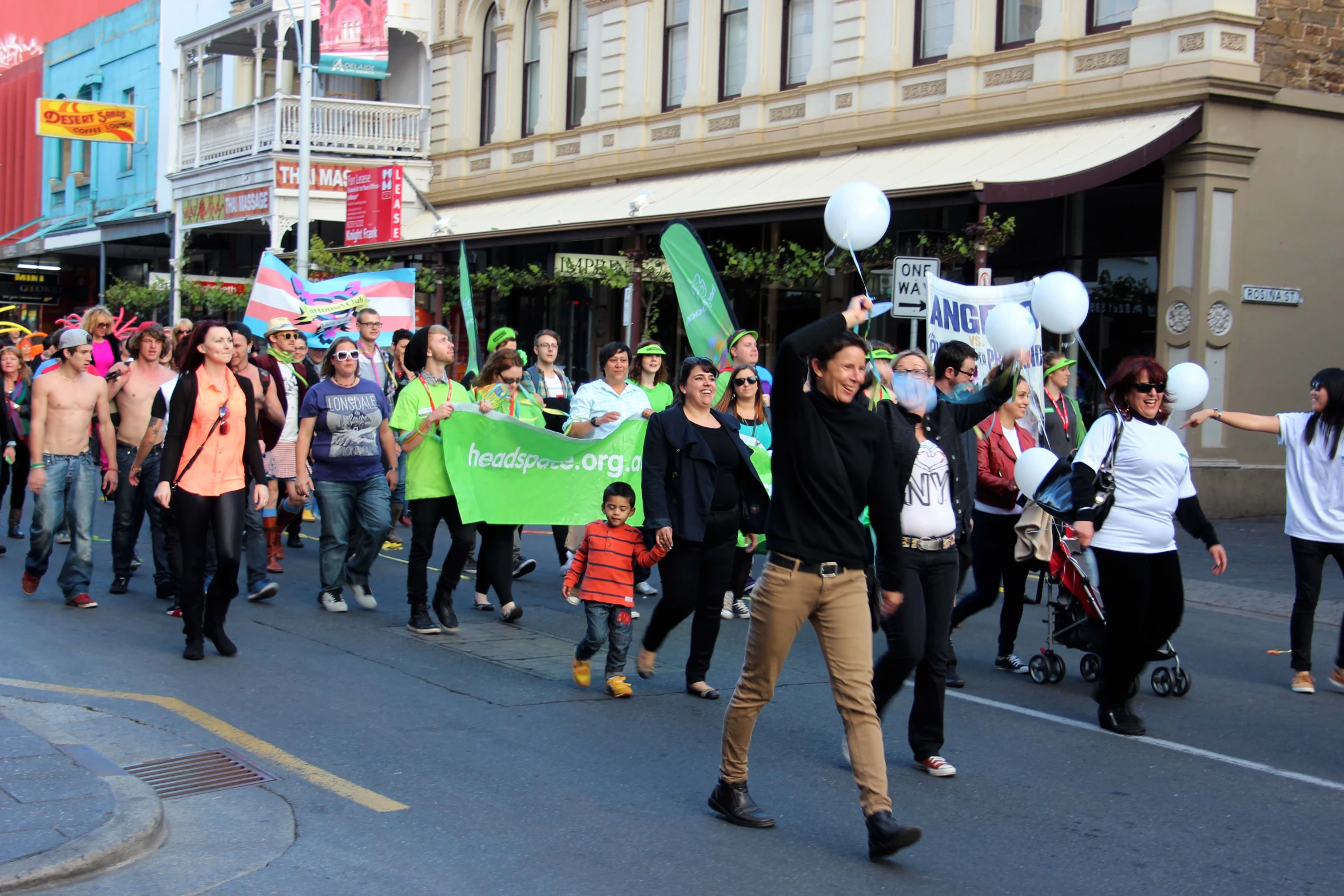 a group of people holding a banner and balloons on a street