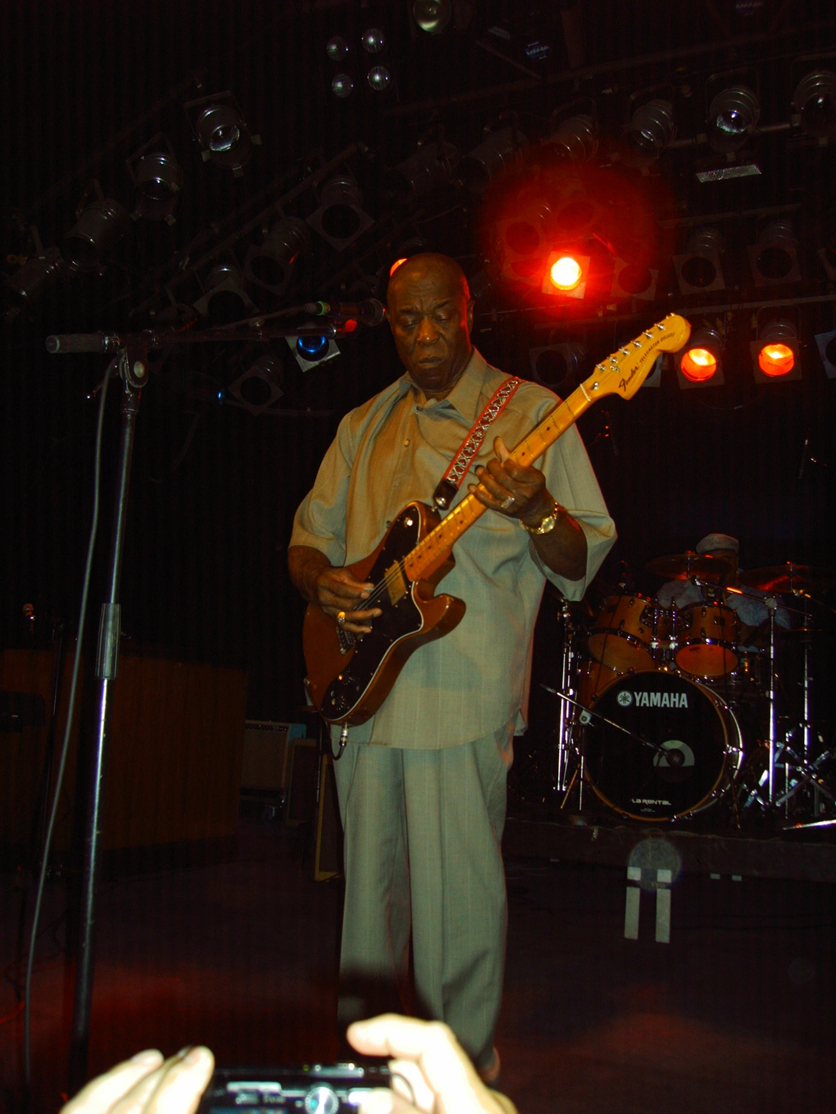 man holding guitar in front of a microphone and red light