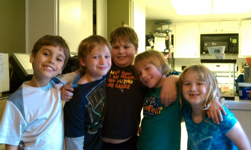 five young children pose in a kitchen in front of the oven