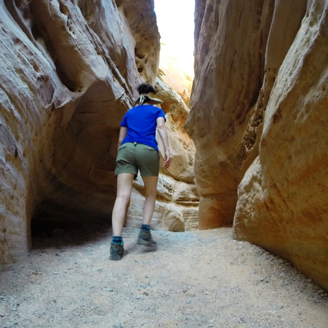 a person in green shorts walking along a narrow passageway