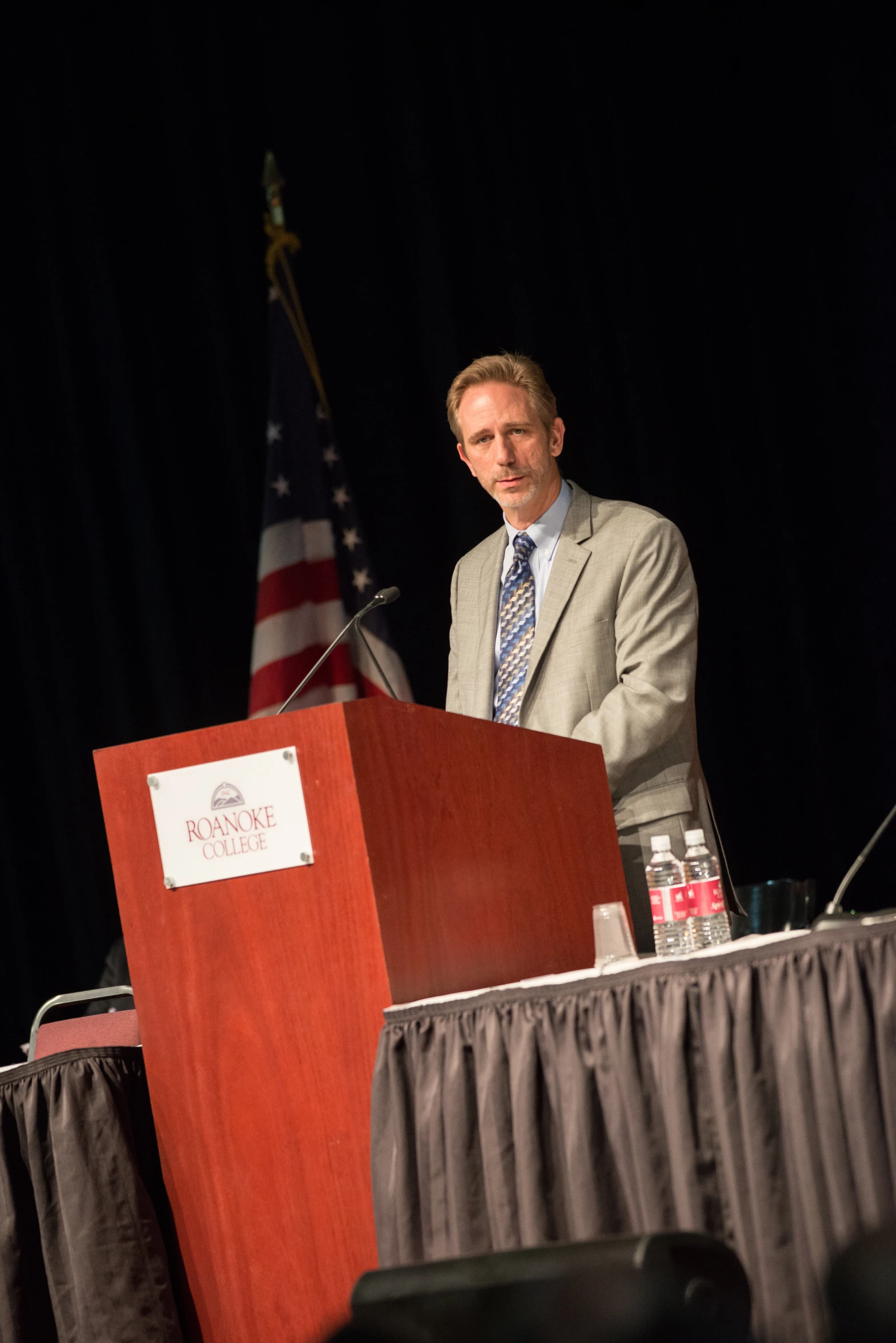 a man standing at a podium while wearing a suit