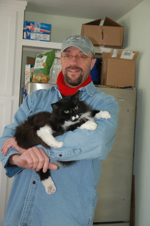 a man is smiling while holding a black and white cat