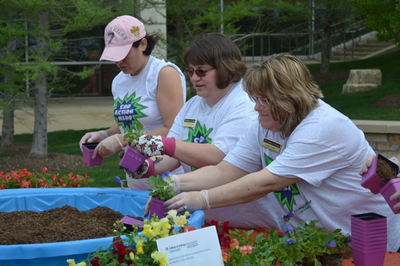 a group of women are weedling and digging flowers