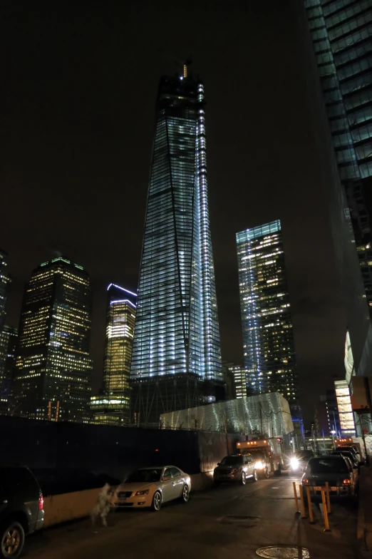 tall skyscrs lit up at night, next to buildings