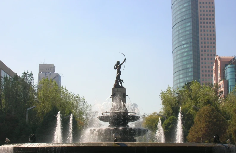 a fountain with a statue holding a bow on top