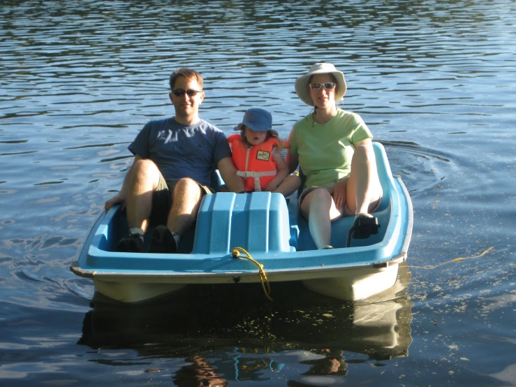 four people in a little boat sitting on a lake