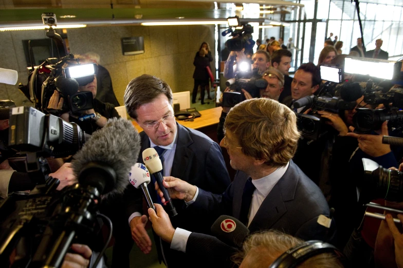 reporters surround a news reporter holding microphones and recording them