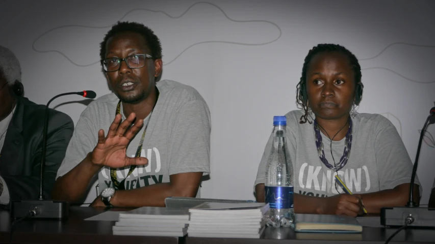 two people are sitting at a table in front of microphones