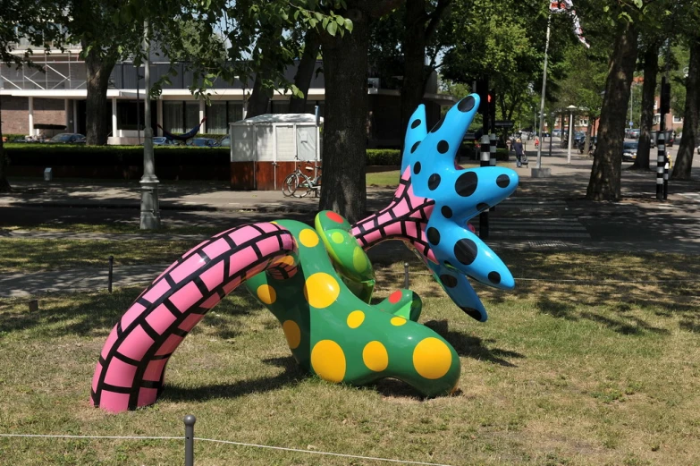 two giant painted animals next to a tree on the grass