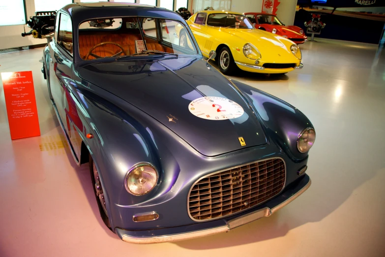 two classic sports cars on display in a museum