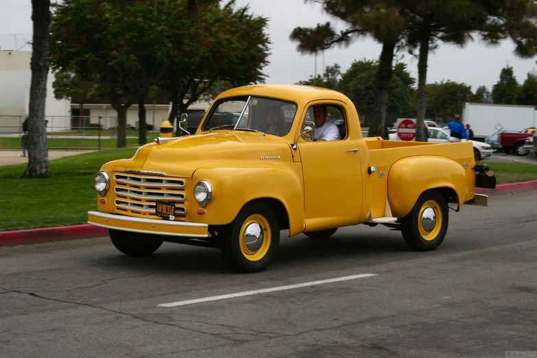 a yellow vintage truck that has people in the bed