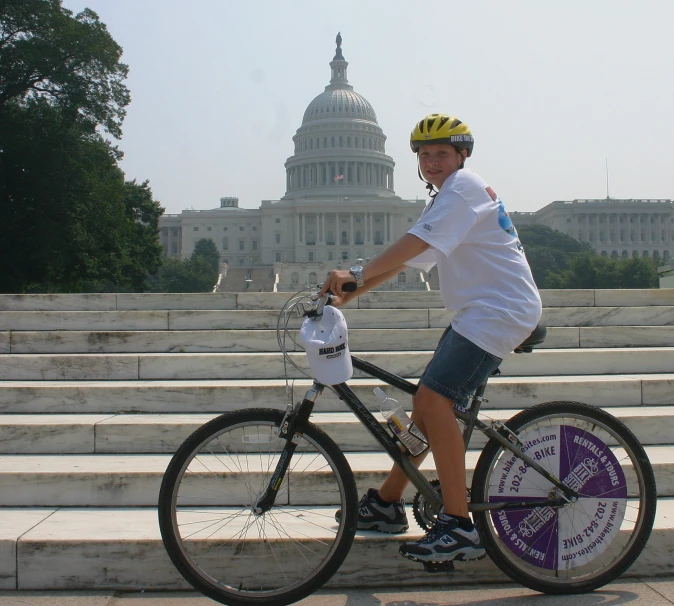 there is a man posing with his bike in front of the capital building