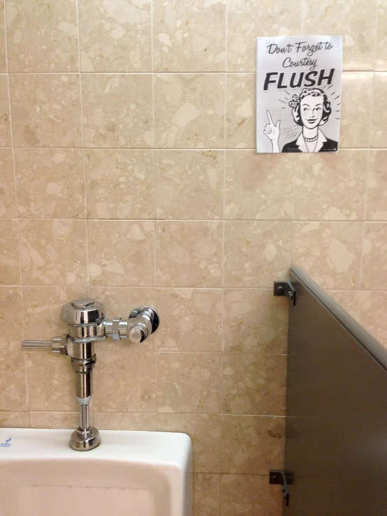 a urinal and sign on a beige tile wall