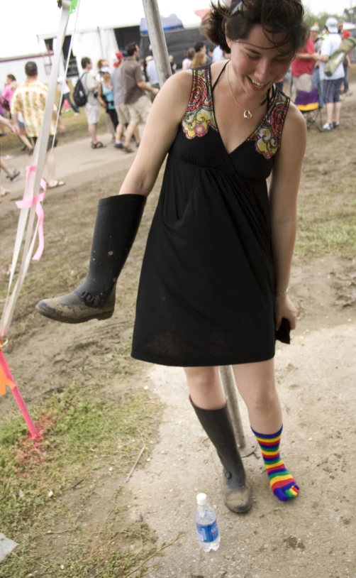 a woman with dark hair and a multi - colored hat carries a broken umbrella