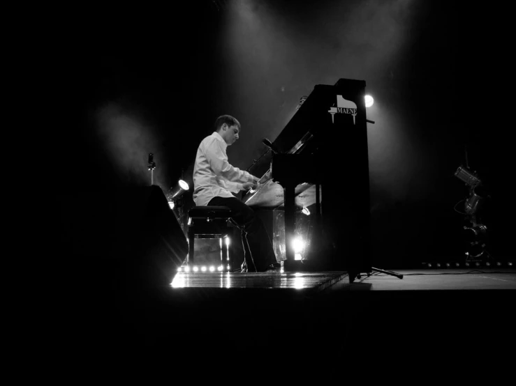 a man playing the piano in front of two lights