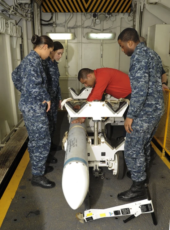 two navy personnel examine a model of a rocket