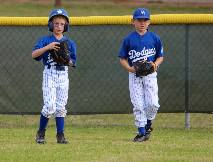 two s in baseball uniforms holding their mitts