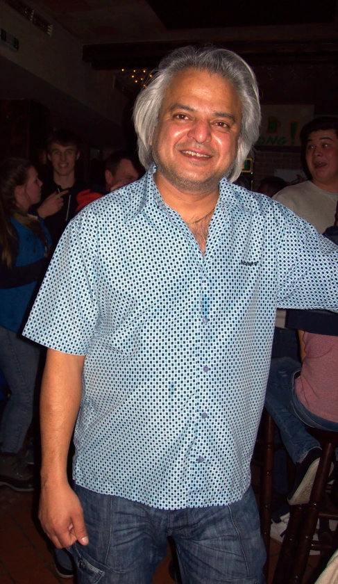 a man wearing a blue on up shirt and jeans