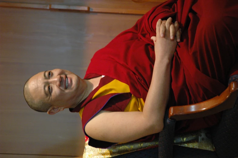 a smiling man wearing a robe sitting in a chair