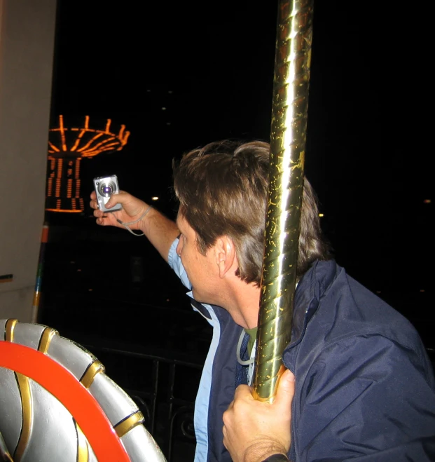 a man holding up a cell phone in front of a ferris wheel