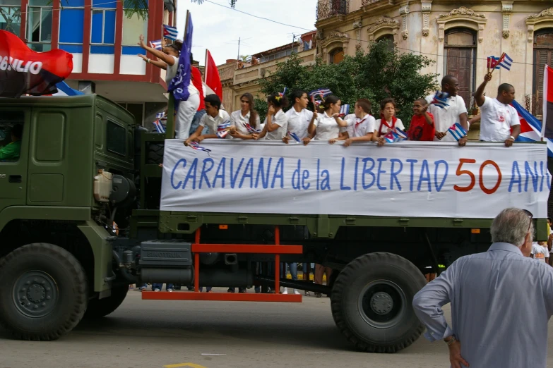 a large truck carrying a parade with a group of people riding on the back of it