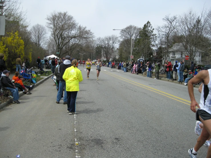 people are walking down a long road near many spectators