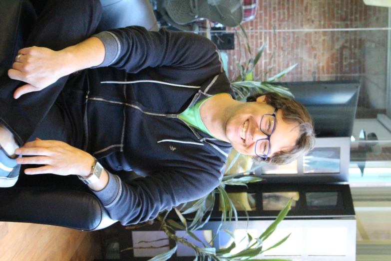 a man wearing glasses sitting down on top of a chair