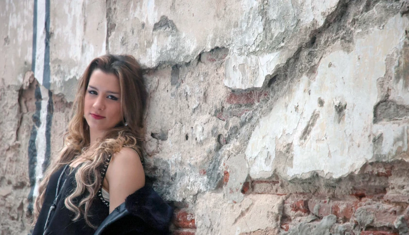 young woman posing against a wall next to brick building