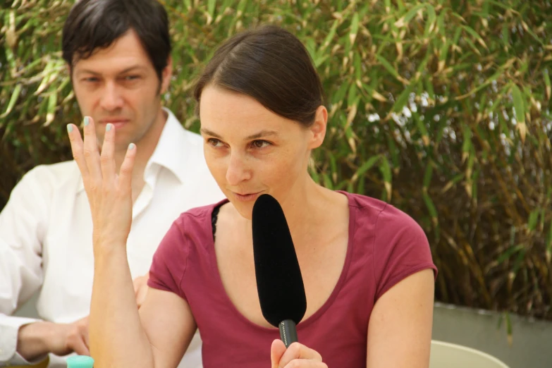 a woman sitting next to a man making the hand gesture with her finger